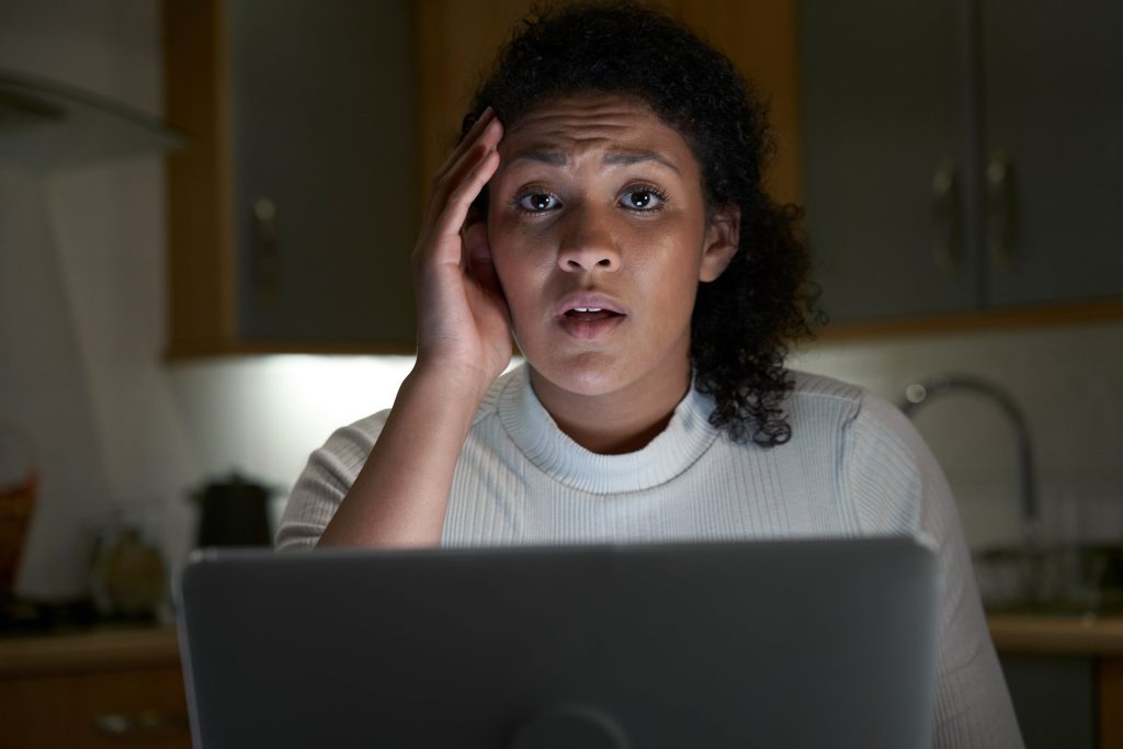 Worried woman in front of a laptop at night.