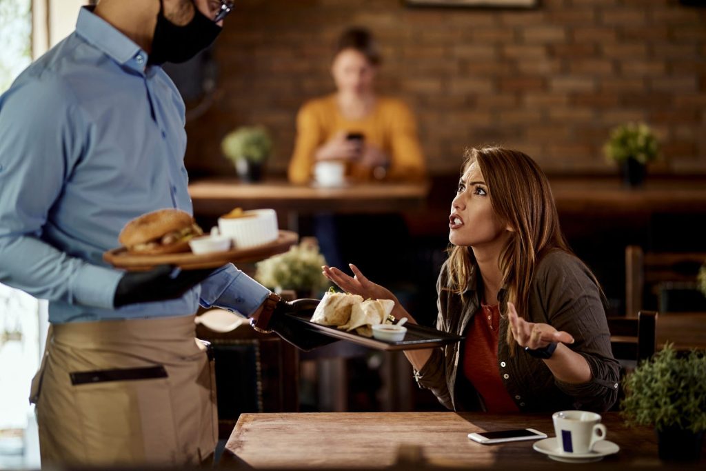 Woman arguing with a waiter in a restaurant about her order.
