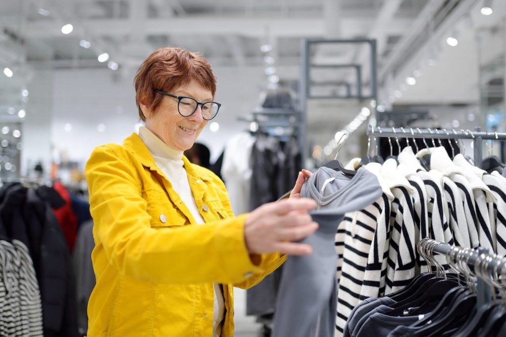 9 Things Retirees Should Stop Buying, According to Financial Experts Senior woman shopping for clothes