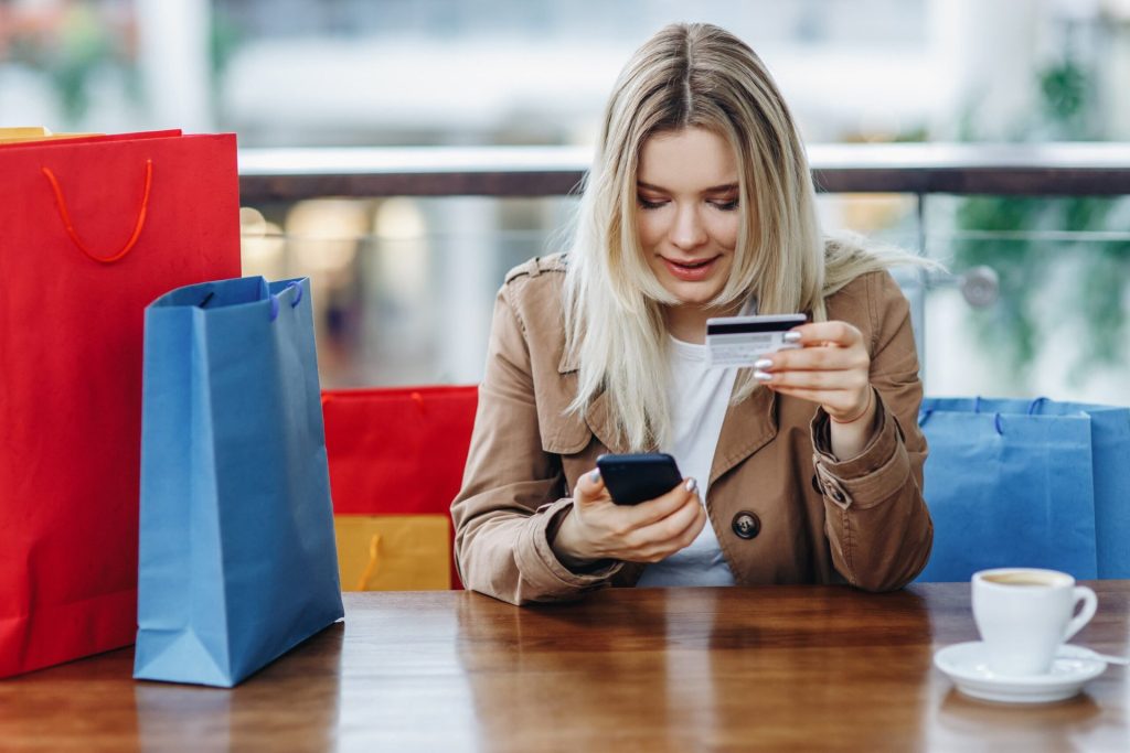 Woman at a mall with purchase, buying more online. Too much shopping and buying. Out of control spending.