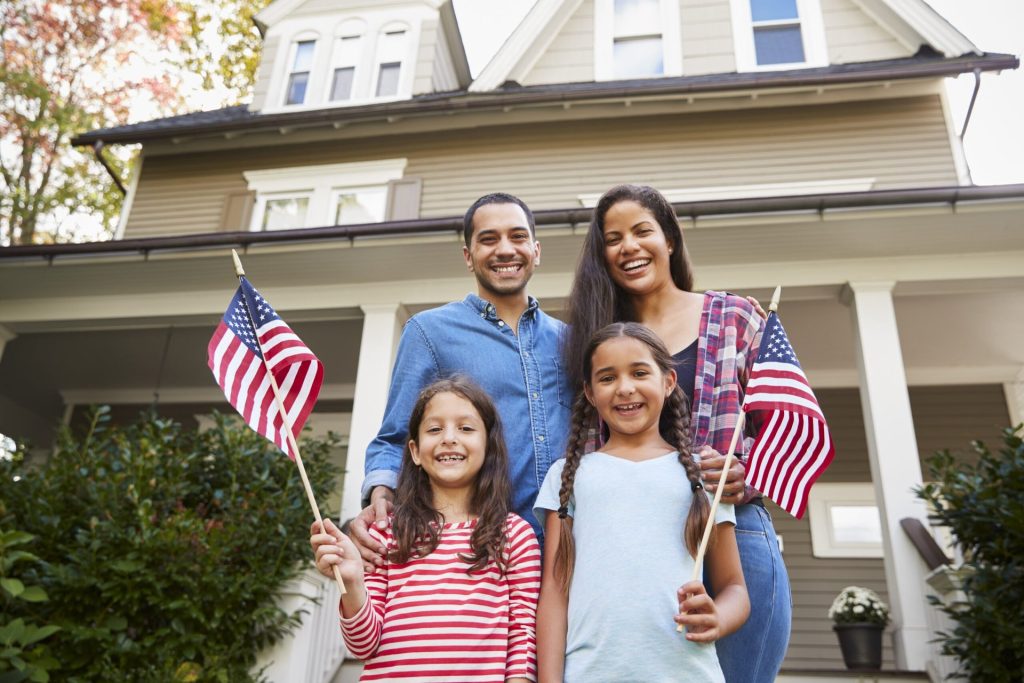 Family outside their home waving American flags