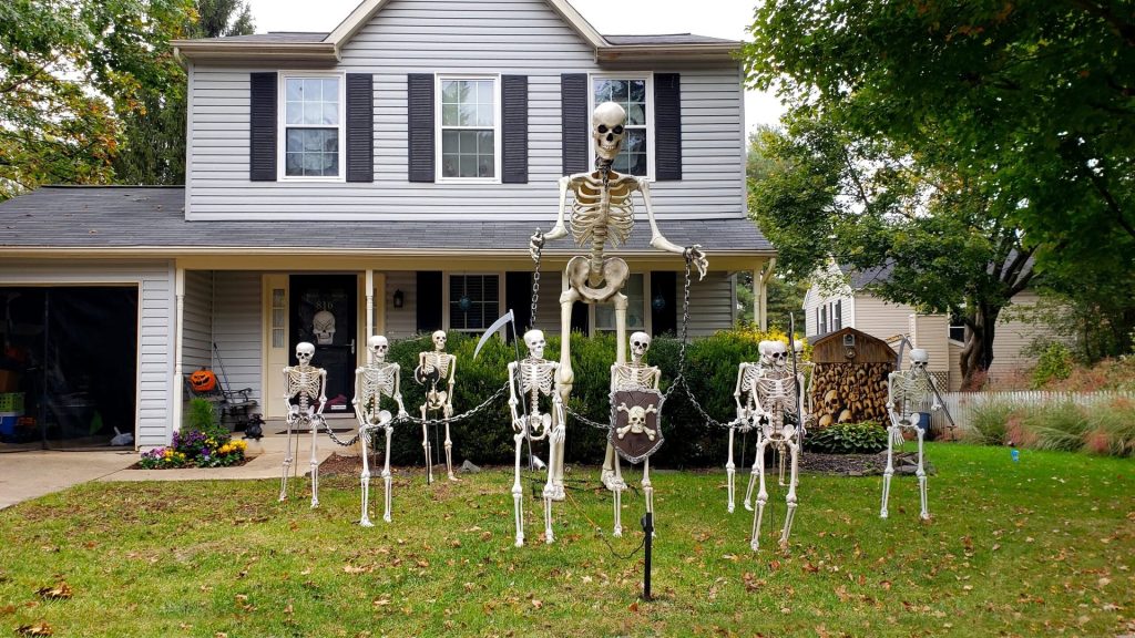 Skeleton decorations for Halloween on a lawn in front of a house.