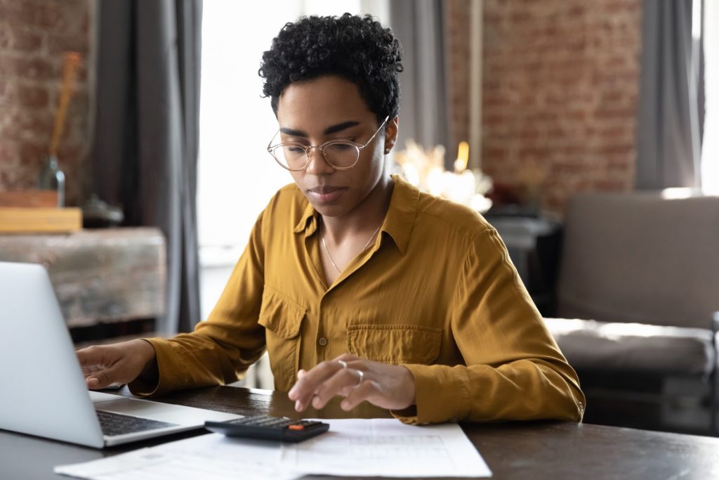 Woman doing taxes at computer with calculator
