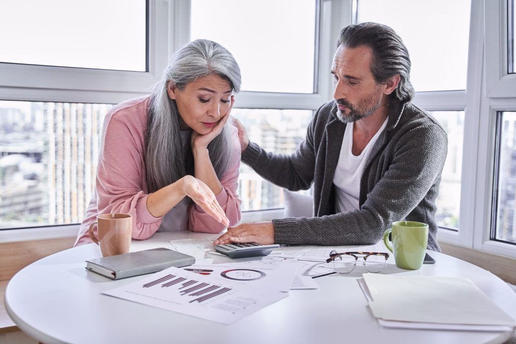 Worried and stressed senior couple paying bills and working on budget