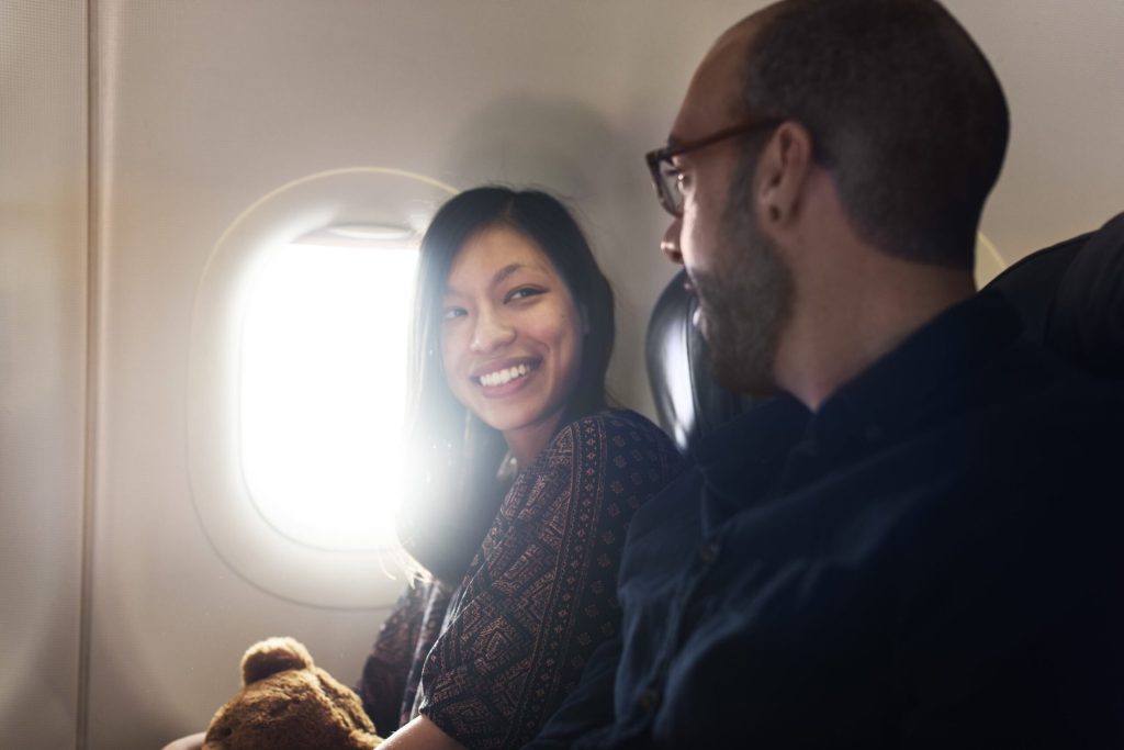 Two people smile and talk on an airplane